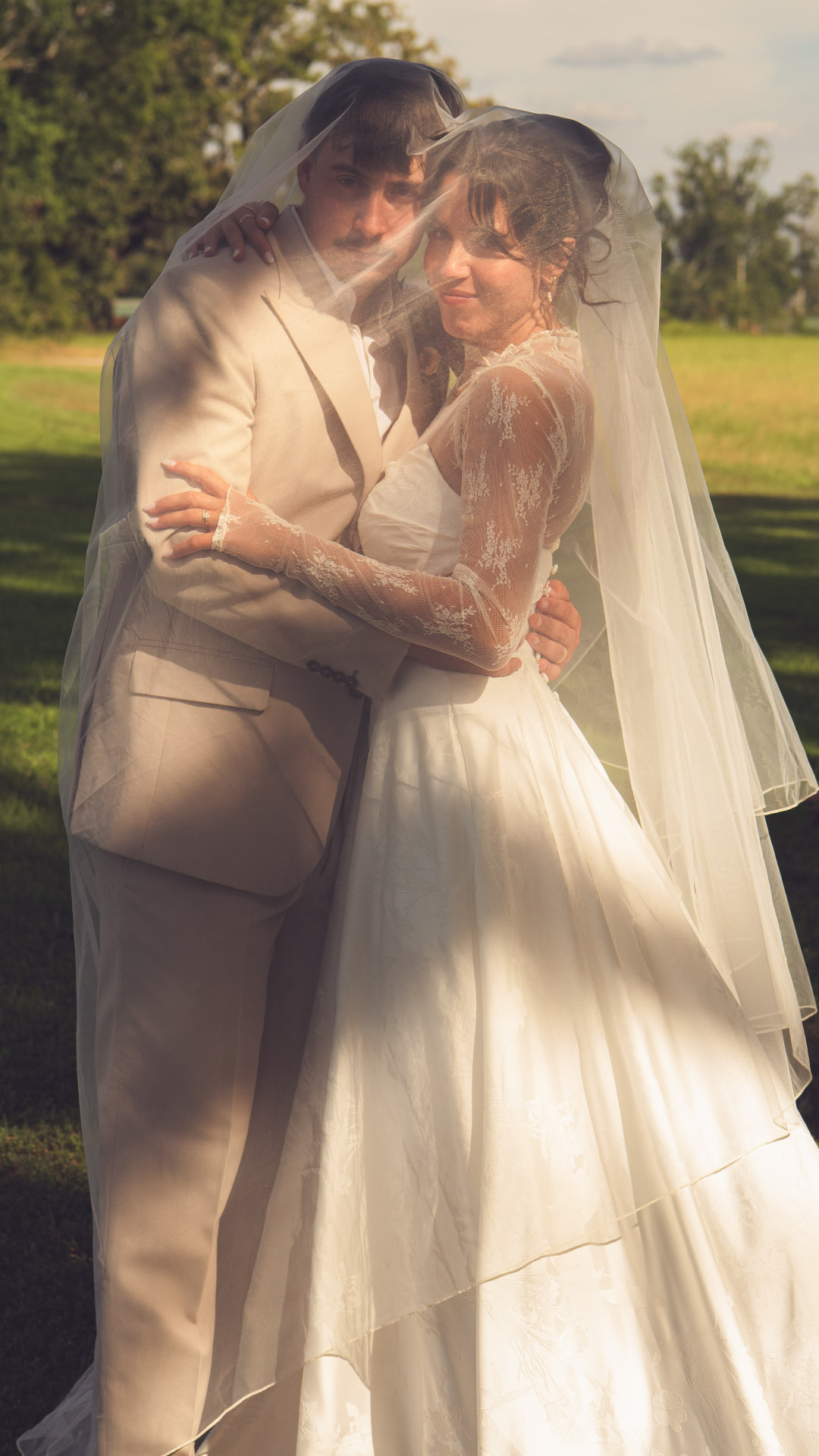 A bride and groom wrapped together under a veil
